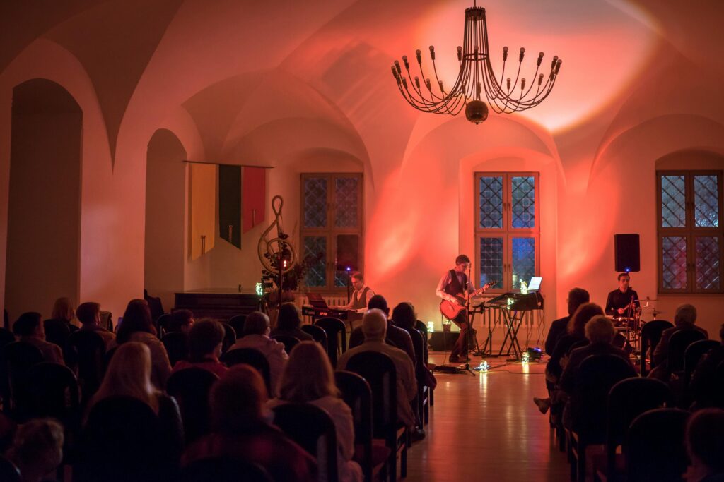 Intimate indoor concert with live band musicians performing under warm lighting.